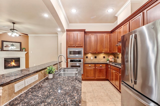 kitchen with stainless steel appliances, sink, backsplash, dark stone counters, and crown molding