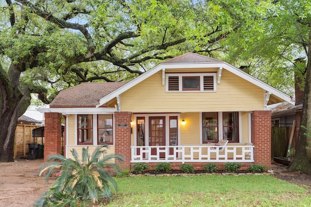 bungalow-style home featuring brick siding, covered porch, and a front lawn