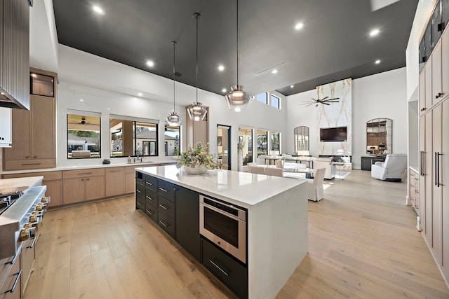 kitchen with sink, decorative light fixtures, ceiling fan, built in microwave, and a large island