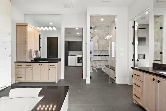 bathroom with vanity, a shower with door, and washing machine and clothes dryer