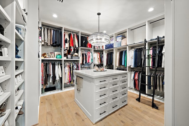 walk in closet featuring light hardwood / wood-style flooring and a notable chandelier