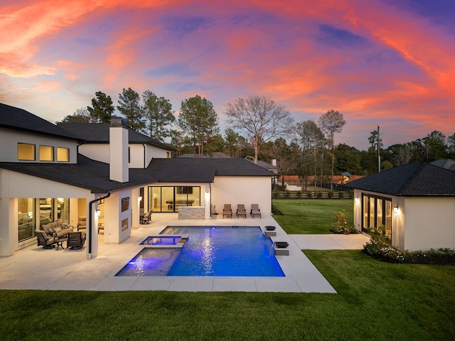 back house at dusk with an outdoor living space, a swimming pool with hot tub, a patio area, and a yard