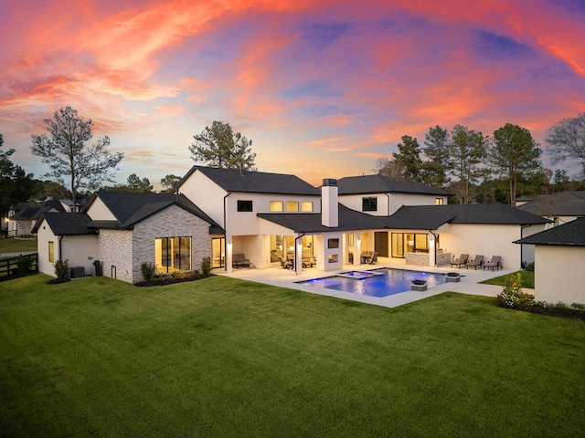 back house at dusk with a yard, an outdoor hangout area, and a patio area