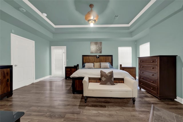 bedroom with dark hardwood / wood-style floors and a raised ceiling