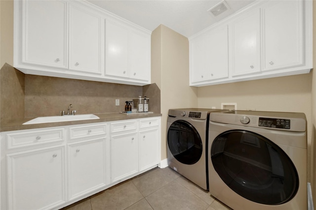 washroom with washing machine and clothes dryer, sink, light tile patterned floors, and cabinets