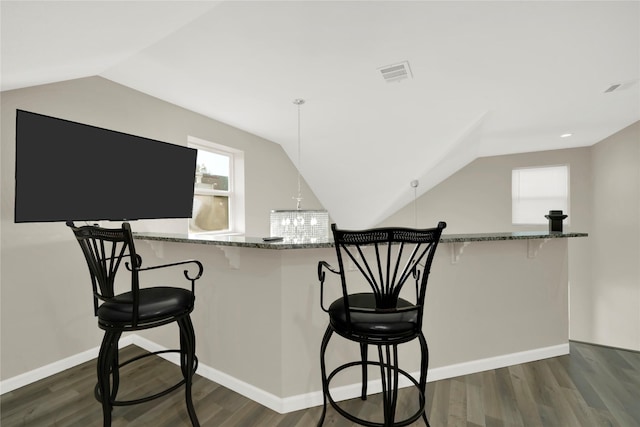 kitchen featuring kitchen peninsula, a kitchen breakfast bar, and dark wood-type flooring