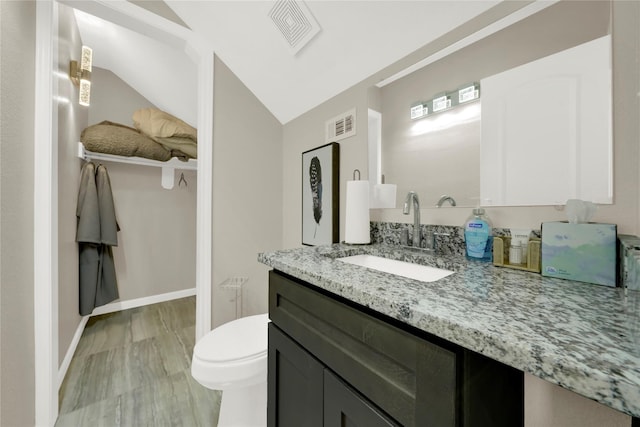 bathroom featuring hardwood / wood-style floors, vanity, vaulted ceiling, and toilet