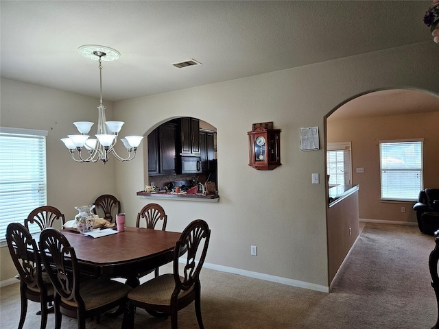 carpeted dining area featuring an inviting chandelier