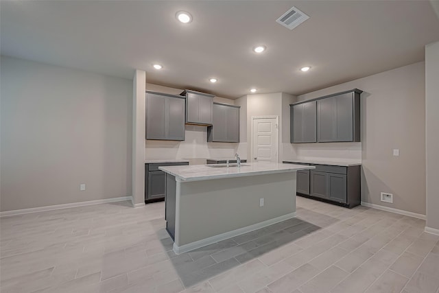 kitchen featuring a center island with sink, gray cabinetry, and sink