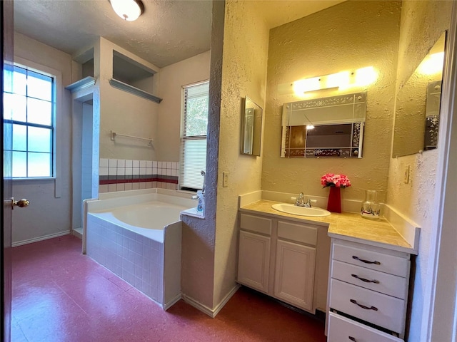 bathroom featuring a relaxing tiled tub, a textured ceiling, and vanity