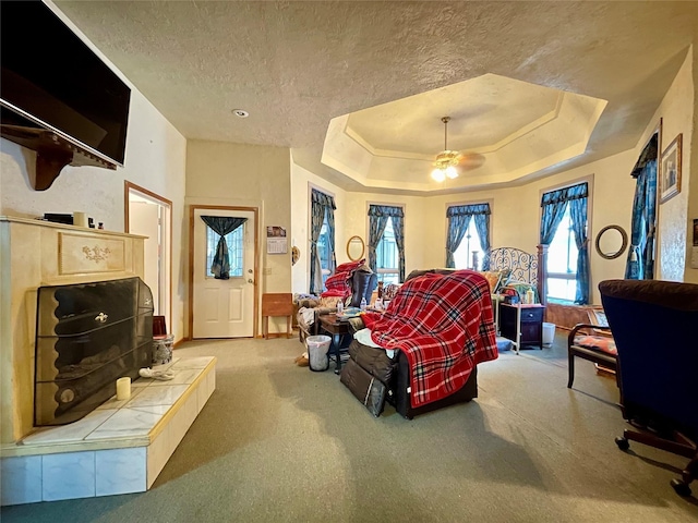 bedroom with a raised ceiling, ceiling fan, carpet floors, and a textured ceiling