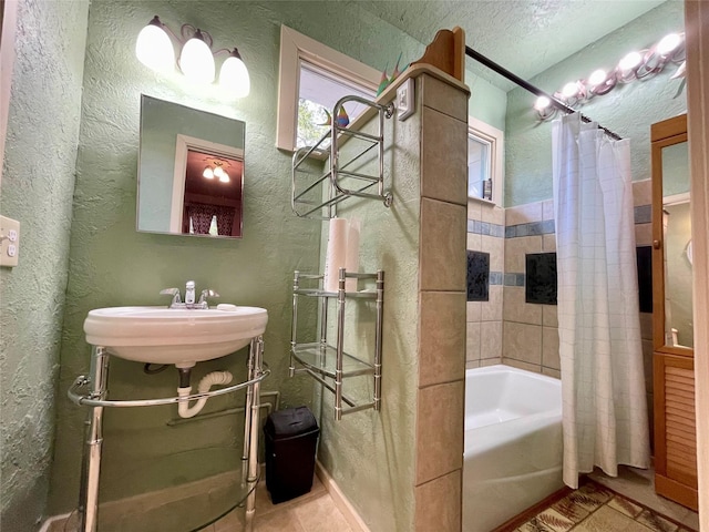 bathroom with tile patterned floors, sink, shower / bathtub combination with curtain, and a textured ceiling