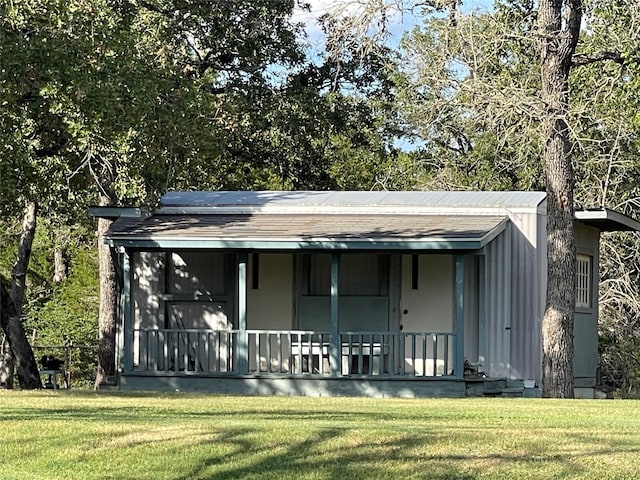 back of property with covered porch and a yard