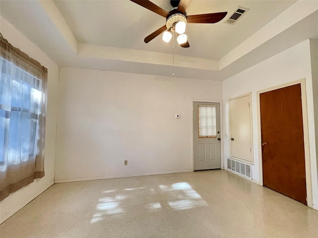 spare room featuring ceiling fan and a raised ceiling