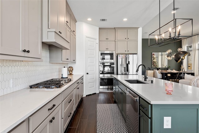 kitchen featuring sink, an inviting chandelier, an island with sink, pendant lighting, and appliances with stainless steel finishes