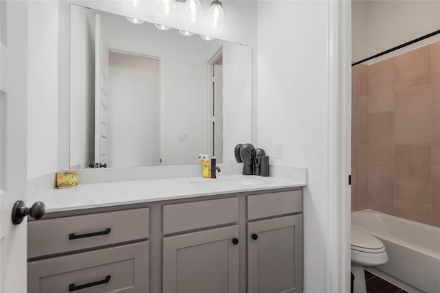 full bathroom featuring vanity, tiled shower / bath, and toilet