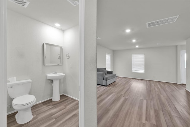 bathroom with toilet, wood-type flooring, and sink