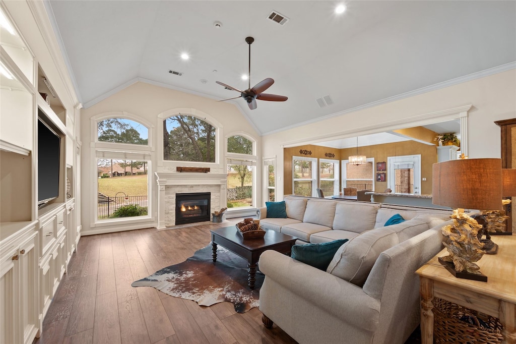 living room with a healthy amount of sunlight, vaulted ceiling, ceiling fan with notable chandelier, and ornamental molding