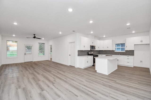 kitchen with ceiling fan, a center island, white cabinetry, and stainless steel appliances