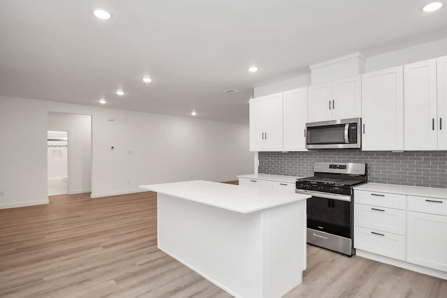 kitchen featuring white cabinets, stainless steel appliances, a kitchen island, and light hardwood / wood-style flooring