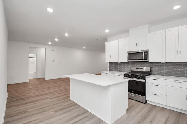 kitchen with white cabinets, a kitchen island, appliances with stainless steel finishes, and light hardwood / wood-style flooring