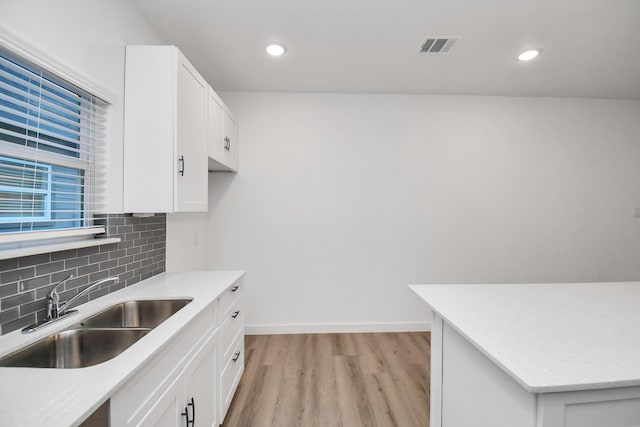 kitchen featuring light wood-type flooring, tasteful backsplash, white cabinetry, and sink