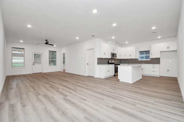 kitchen with stainless steel appliances, a kitchen island, white cabinetry, and ceiling fan