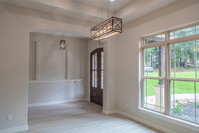 entrance foyer with french doors, a chandelier, and light hardwood / wood-style flooring