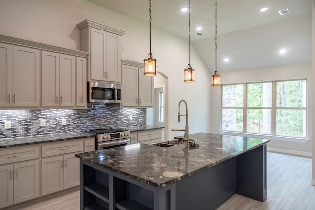 kitchen with sink, hanging light fixtures, an island with sink, vaulted ceiling, and appliances with stainless steel finishes