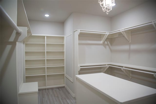 walk in closet with a chandelier and light hardwood / wood-style flooring