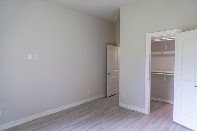 unfurnished bedroom featuring a spacious closet, light hardwood / wood-style flooring, and a closet