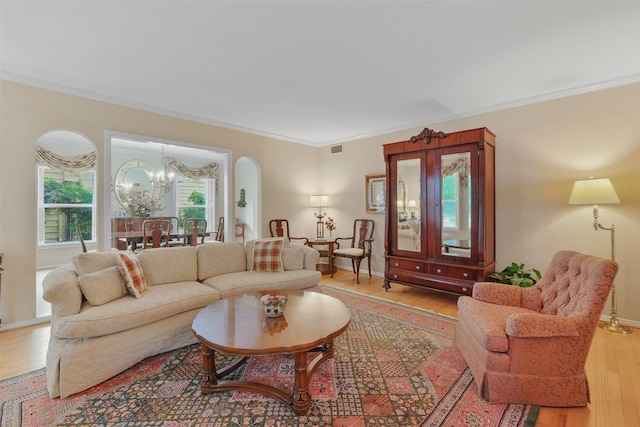 living room featuring light hardwood / wood-style floors, ornamental molding, and a chandelier