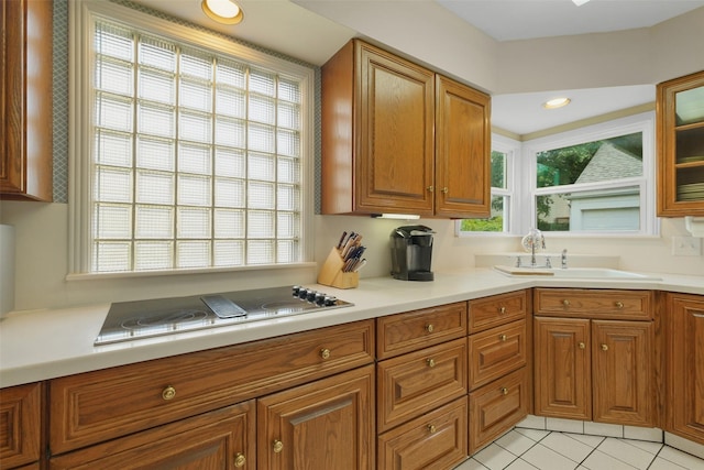 kitchen with cooktop, a wealth of natural light, sink, and light tile patterned floors