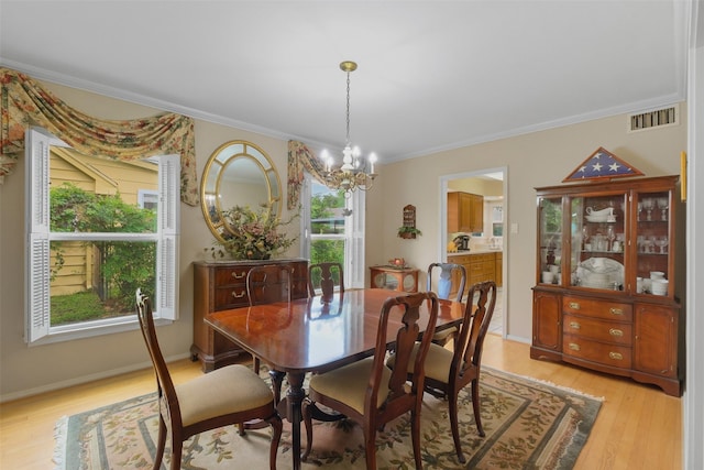 dining room featuring crown molding, light hardwood / wood-style flooring, and a notable chandelier