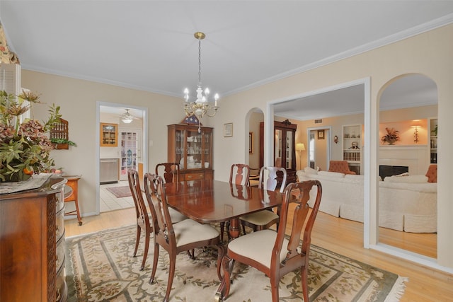 dining room featuring built in features, light hardwood / wood-style floors, an inviting chandelier, and crown molding