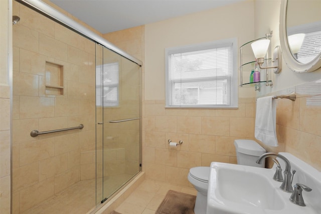 bathroom featuring sink, tile patterned floors, toilet, a shower with shower door, and tile walls