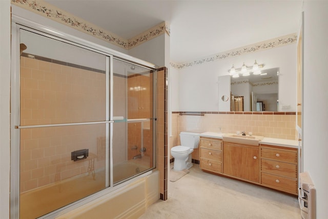 full bathroom with heating unit, toilet, shower / bath combination with glass door, vanity, and tile walls