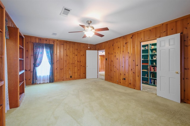 interior space with ceiling fan and wood walls