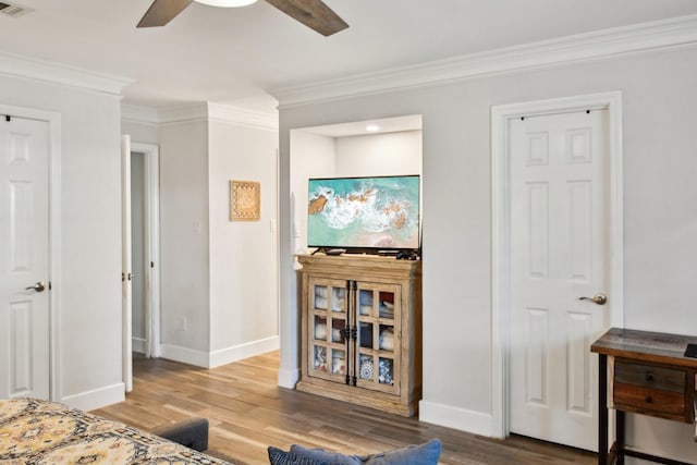 bedroom featuring hardwood / wood-style flooring, ceiling fan, and crown molding