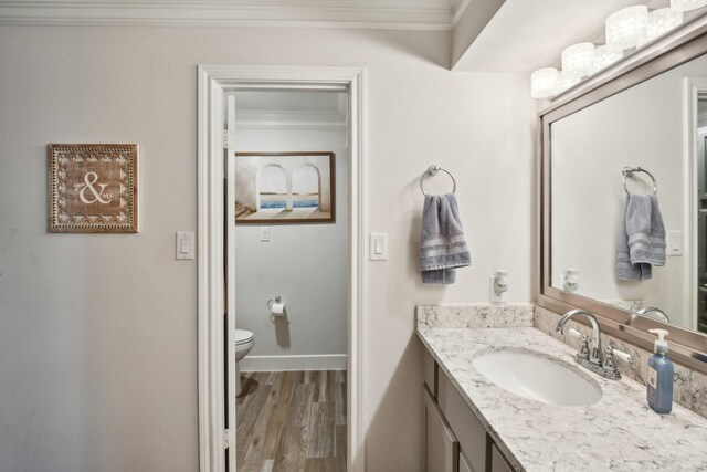 bathroom with vanity, toilet, wood-type flooring, and crown molding