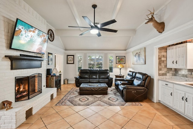 tiled living room featuring vaulted ceiling with beams, ceiling fan, ornamental molding, and a fireplace