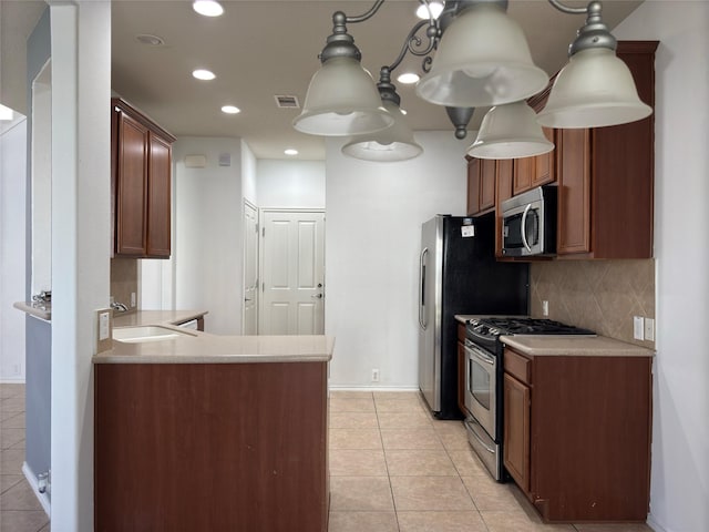 kitchen featuring sink, backsplash, kitchen peninsula, light tile patterned flooring, and appliances with stainless steel finishes