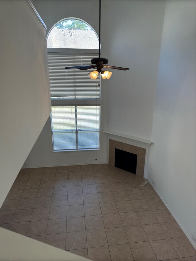 unfurnished living room featuring a tiled fireplace, ceiling fan, and light tile patterned flooring