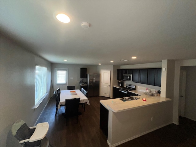 kitchen with sink, kitchen peninsula, dark wood-type flooring, and appliances with stainless steel finishes