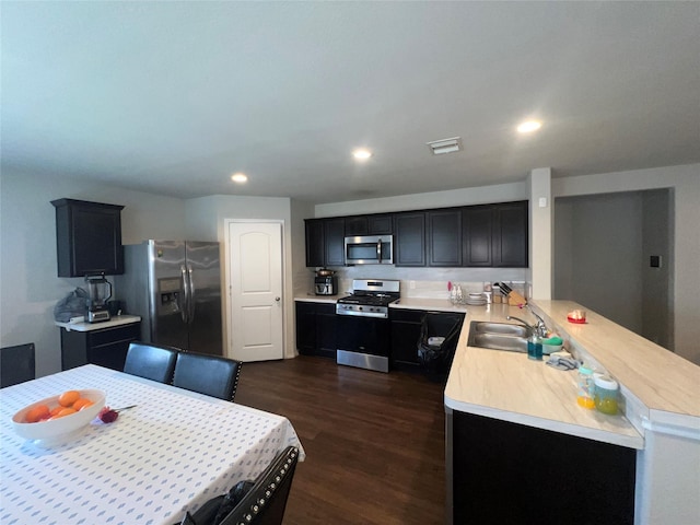 kitchen with kitchen peninsula, appliances with stainless steel finishes, dark wood-type flooring, and sink