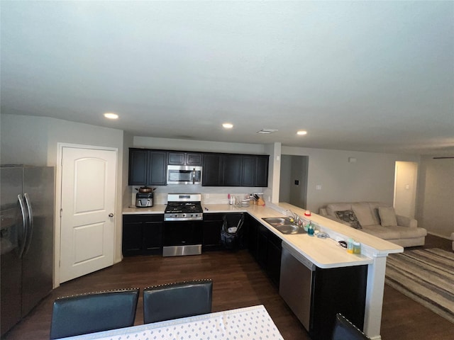 kitchen featuring sink, stainless steel appliances, dark hardwood / wood-style flooring, kitchen peninsula, and a breakfast bar area