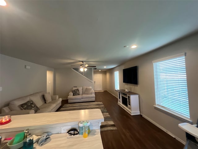 living room featuring ceiling fan and dark wood-type flooring