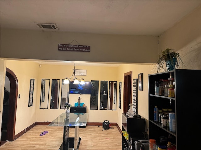 exercise room with hardwood / wood-style floors and a notable chandelier