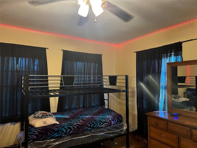 bedroom with hardwood / wood-style flooring, ceiling fan, and a textured ceiling