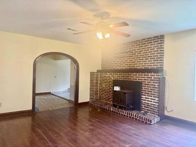 unfurnished living room with a wood stove, dark hardwood / wood-style floors, and ceiling fan